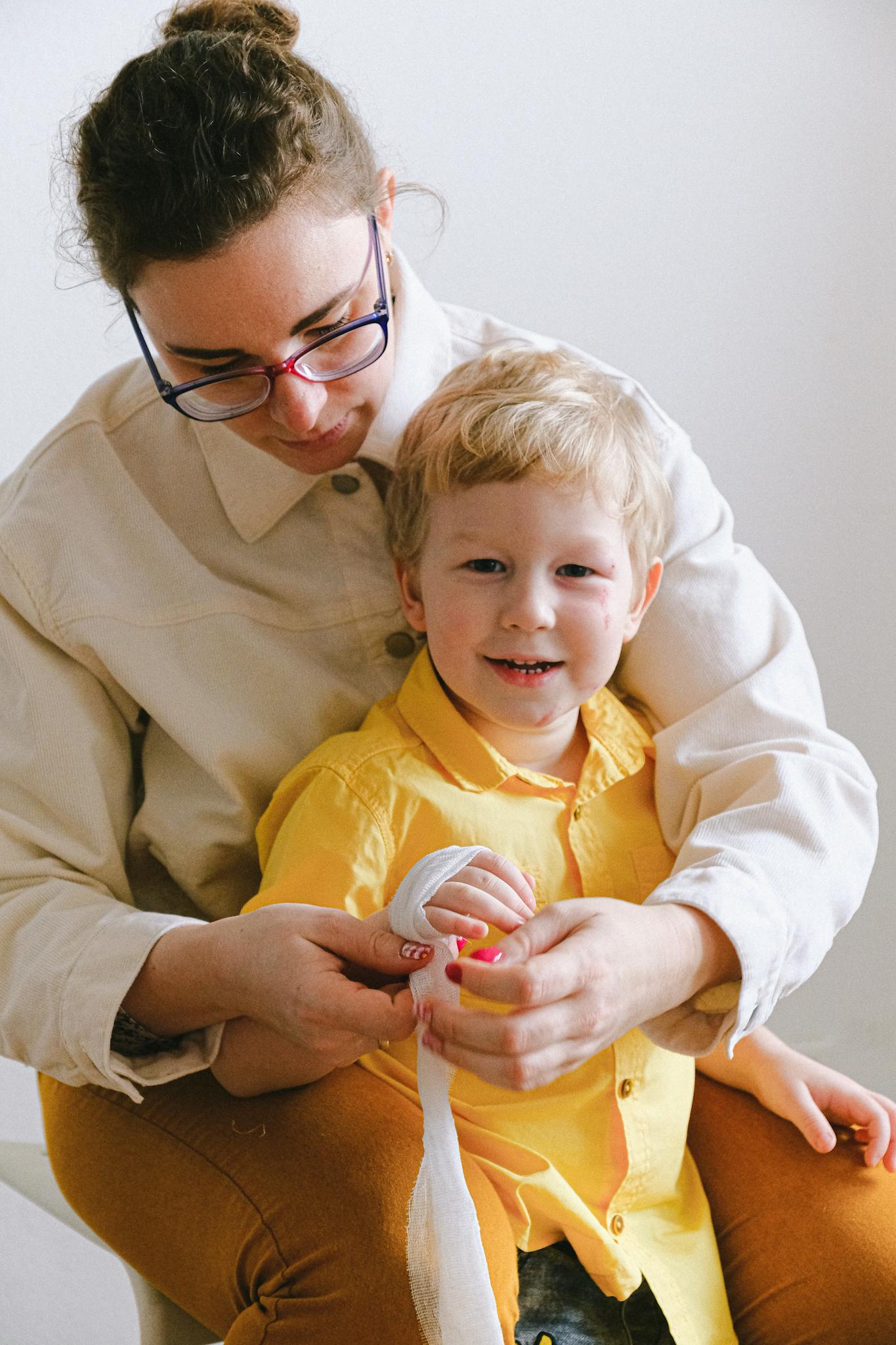 Mother lovingly tends to her son's injured hand, creating a heartwarming scene of care and affection.